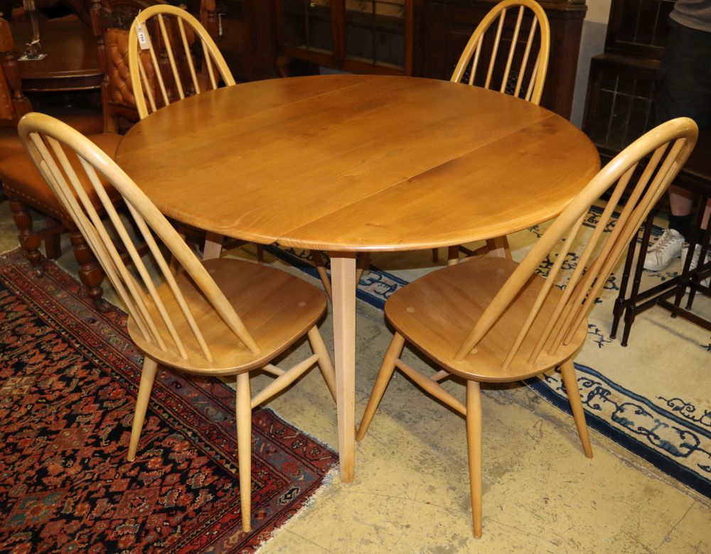 An Ercol circular elm and beech drop leaf dining table, 110cm diameter and four Ercol Windsor beech comb back dining chairs